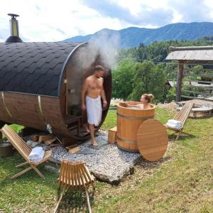 a man standing next to a barrel and a man standing in a bath tub at PUŽMAN Farm Glamping in Radovljica