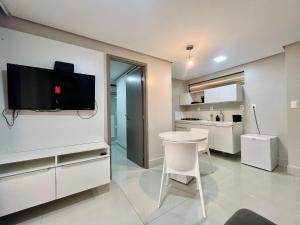 a kitchen with a table and a tv on a wall at Cabo Branco - Fortune in Tambaú