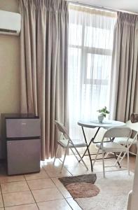 a living room with a table and chairs and a window at Durban Oceanic Apartment 117 in Durban