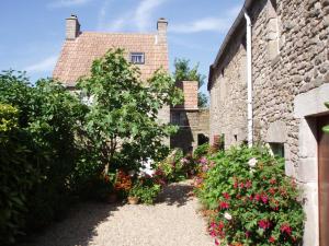 an old stone house with flowers in front of it at La petite maison du cap in Omonville-la-Rogue