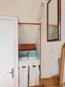 a small bathroom with a sink and a mirror at La petite maison du cap in Omonville-la-Rogue