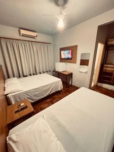 a hotel room with two beds and a television at Hotel América in Ivaiporã