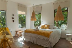 a bedroom with a bed and two windows at Selvática Residences in Puerto Viejo