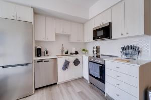 a kitchen with white cabinets and white appliances at Modern Downtown Condo with Gym in Kitchener +26 photos