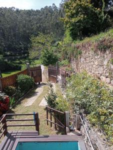 a swimming pool with two benches next to a stone wall at Casa da Maria Gata in Sever do Vouga +16 photos