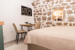 a bedroom with a stone wall with a bed and a table at Apartmani Kostic in Tivat