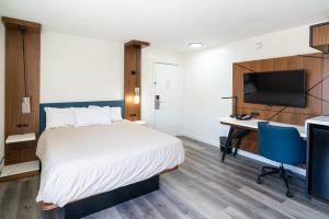a hotel room with a bed and a desk and a tv at Central Phoenix Hotel in Phoenix