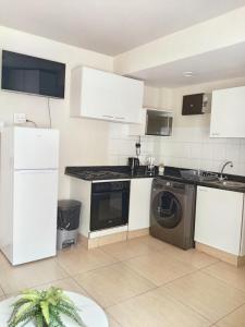 a kitchen with white appliances and a washer and dryer at Durban Oceanic Apartment 82B in Durban