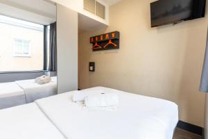 two beds in a room with a tv on the wall at easyHotel Liverpool in Liverpool