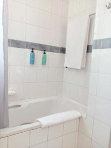 a white bathroom with a tub and two blue bottles at Durban Oceanic Apartment 82B in Durban +14 photos