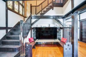 a living room with a staircase and a large tv at Walkable Schenectady Getaway: 2-Unit Campus Hub in Schenectady