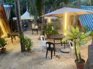 a table with chairs and an umbrella in the sand at Sea Breeze Lodge in Siquijor