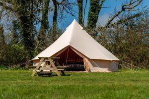 a large tent with a picnic table in a field at Boscoppa Farm-Furnished Bell Tent 4 in St Austell