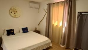 a bedroom with a white bed and a window at Paradies Caraibes IV in Les Abymes