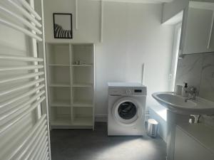 a white bathroom with a washing machine and a sink at Studio spacieux et calme - Parking facile in La Rochefoucauld +4 photos
