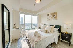 a white bedroom with a large bed with a window at Stylish Open Concept Condo with Gym in Kitchener