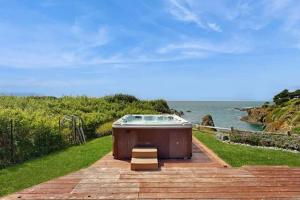 a hot tub sitting on a patio near the ocean at Remodeled oceanfront estate with Studio Cottage in Mendocino