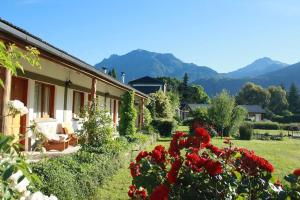 a house with red flowers and mountains in the background at Hosteria El Hoyo in El Hoyo