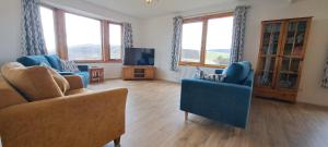 a living room with two blue chairs and a tv at Solheim Self Catering in Whiteness