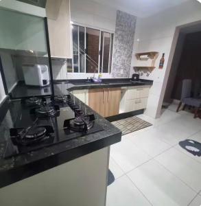 a kitchen with a black counter top with a stove at Refúgio Aconchego in Sorocaba