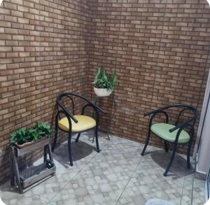 two chairs and a table with plants on a brick wall at Refúgio Aconchego in Sorocaba