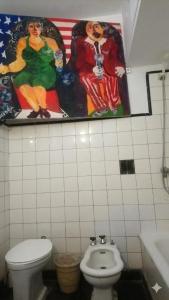 a bathroom with a toilet and a painting on the wall at Casa JINDRA in Puerto Madryn +18 photos
