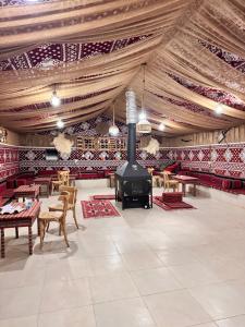 a large room with a fireplace and tables and chairs at Rum Horizon Camp& Tours in Wadi Rum