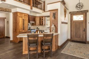 a kitchen with wooden cabinets and a large island with bar stools at Creekside Chalet in Big Sky +30 photos