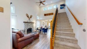 a living room with a staircase with a couch and a fireplace at Riverfront retreat with panoramic river and forest views in Rhododendron +38 photos