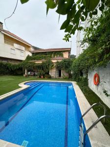 a blue swimming pool in front of a house at Villa del Jerte in El Torno