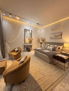 a bedroom with a bed and chairs and a mirror at شاليه هوانا in Sohar