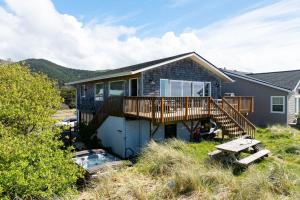 a house with a deck and a bench in front of it at Jettyview Lodge - Meredith Lodging in Nedonna Beach