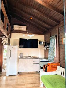 a kitchen with a white refrigerator and a table at Chalé piscina compartilhada com cozinha in Imbituba