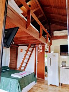 a room with a loft bed with a tv and a refrigerator at Chalé piscina compartilhada com cozinha in Imbituba