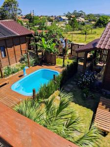 a backyard with a swimming pool and a wooden deck at Chalé piscina compartilhada com cozinha in Imbituba
