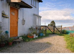 a white building with a wooden door and a fence at Hostal Art Gallery Chiloè in Castro