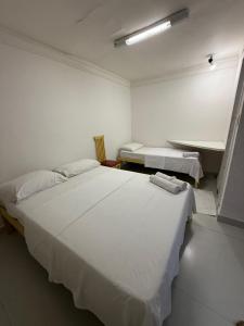 a white room with two beds and a sink at Bahia Executivo Pousada in Zeca