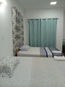 two beds in a room with blue curtains at Hospedaje La Casa del Sauce in Obligado