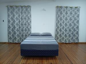 a small bed in a room with two windows at Hospedaje La Casa del Sauce in Obligado