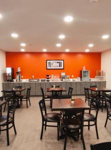 a restaurant with tables and chairs and a kitchen at The Grove Inn and Suites in Eagle Grove