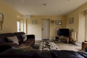 a living room with a couch and a tv at Edensor Cottage Bakewell Peak District in Bakewell