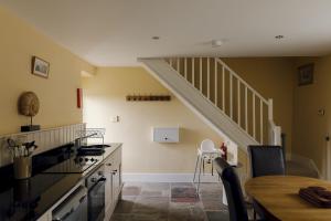a kitchen with a dining table and a staircase at Edensor Cottage Bakewell Peak District in Bakewell