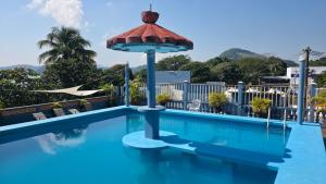 ein Schwimmbecken mit einem Sonnenschirm darüber in der Unterkunft Hotel Juros in Catemaco