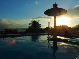 ein Swimmingpool mit Sonnenschirm und Sonnenuntergang in der Unterkunft Hotel Juros in Catemaco