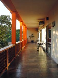 ein leerer Balkon mit orangefarbenen Wänden, Tischen und Stühlen in der Unterkunft Hotel Juros in Catemaco
