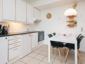 a kitchen with white cabinets and a white table and chairs at 7 person holiday home in Ringkøbing in Ringkøbing