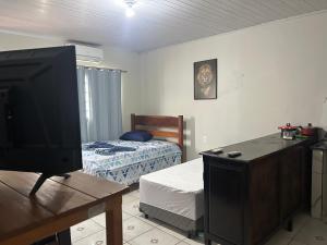 a living room with a television and a bed at Suíte completa com cozinha no centro de Aquidauana in Aquidauana
