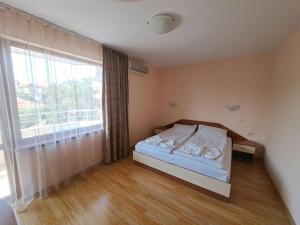 a bedroom with a bed and a large window at Guest House Lazur in Obzor