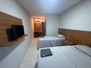 a hotel room with two beds and a flat screen tv at Pousada Complexo Vibe in Baraúna