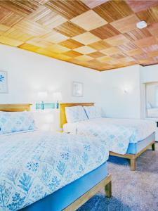 two beds in a bedroom with a wooden ceiling at Fjordline Lodge in Hoodsport